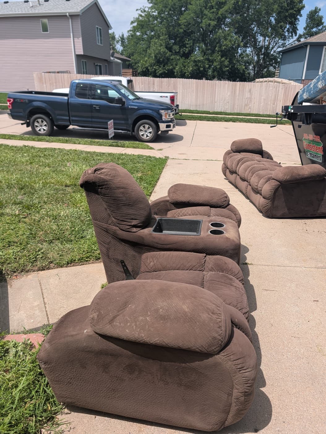 Brown sectional couch sections pulled out to the driveway next to the work truck