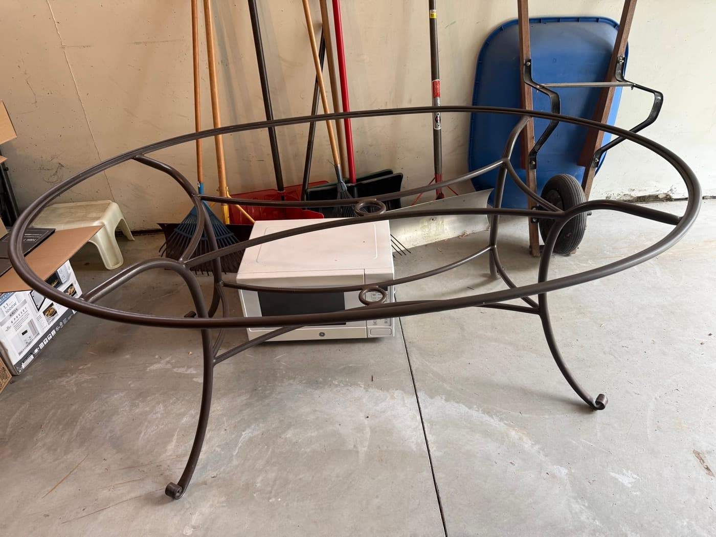 A cluttered garage with an old patio table and household items waiting to be hauled