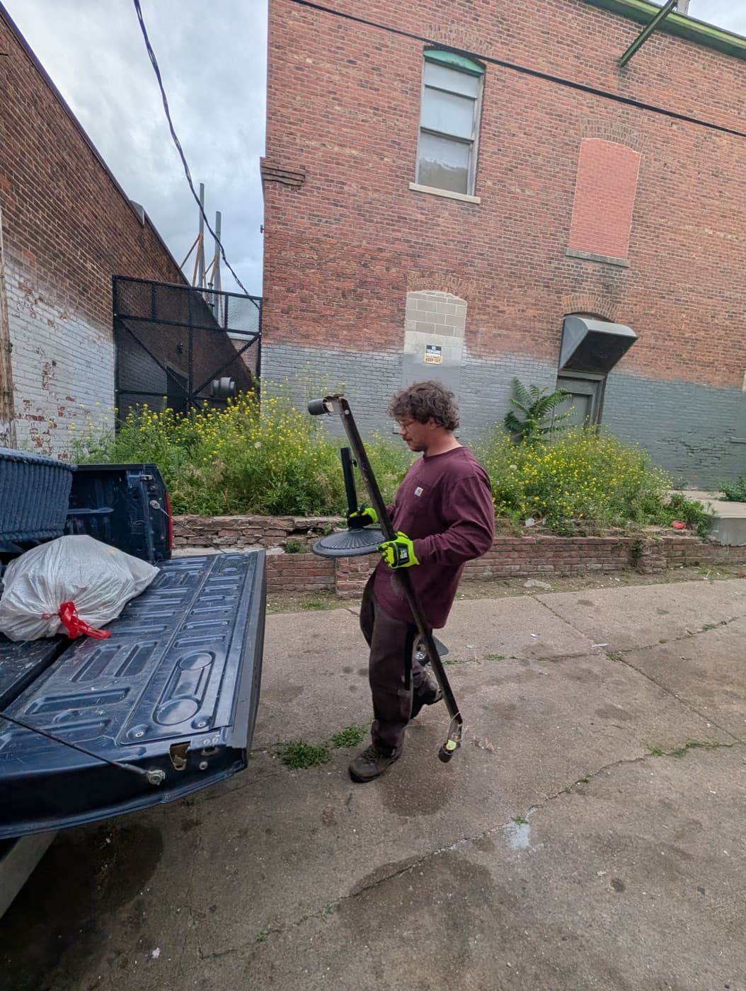 Hampton carrying a heavy metal item to the truck during a cleanout