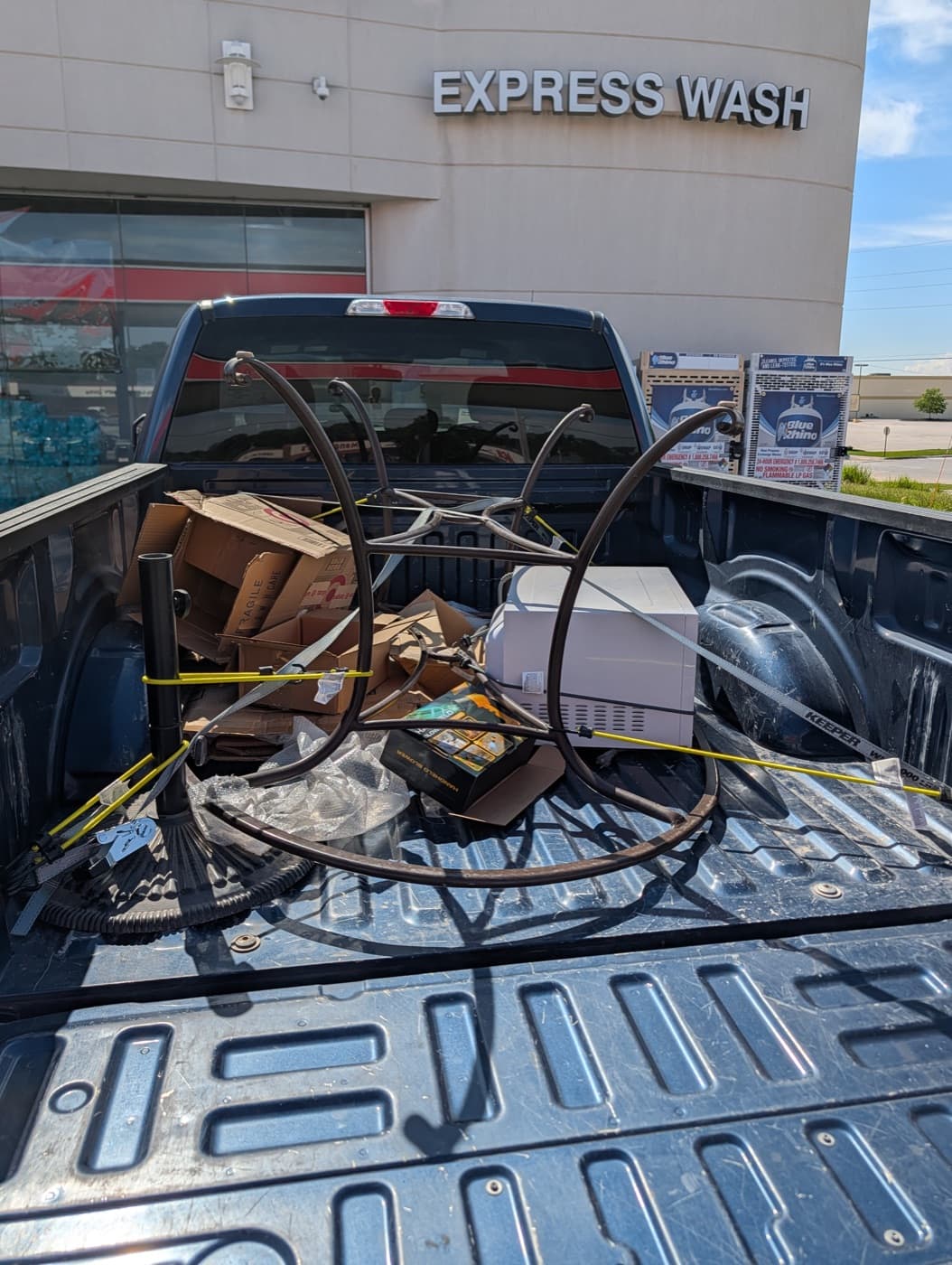 Truck bed loaded with boxes and metal furniture, strapped and ready