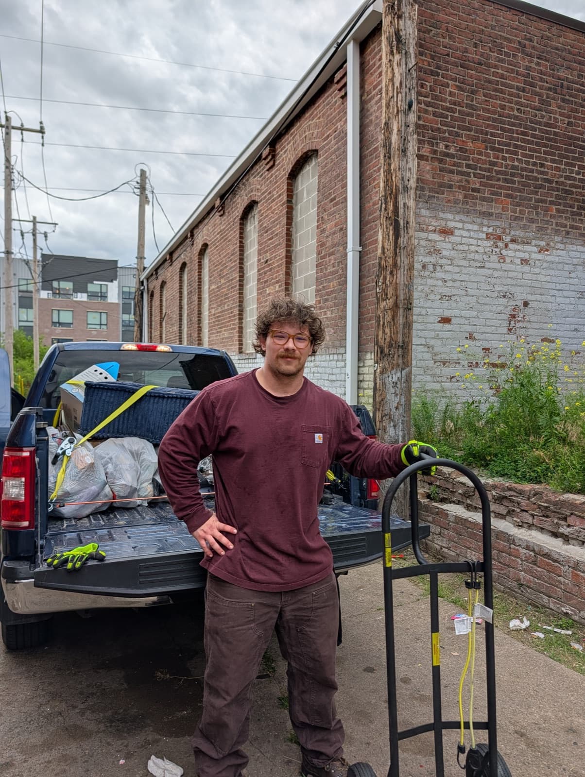 Hampton Kaye-Kuter, owner of Hampton Junk Removal, standing with his work truck and dolly after a cleanout